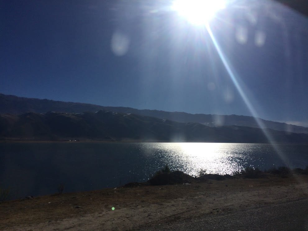 El sol reflejado sobre el agua del dique, a contraluz, desde el camino de la costa